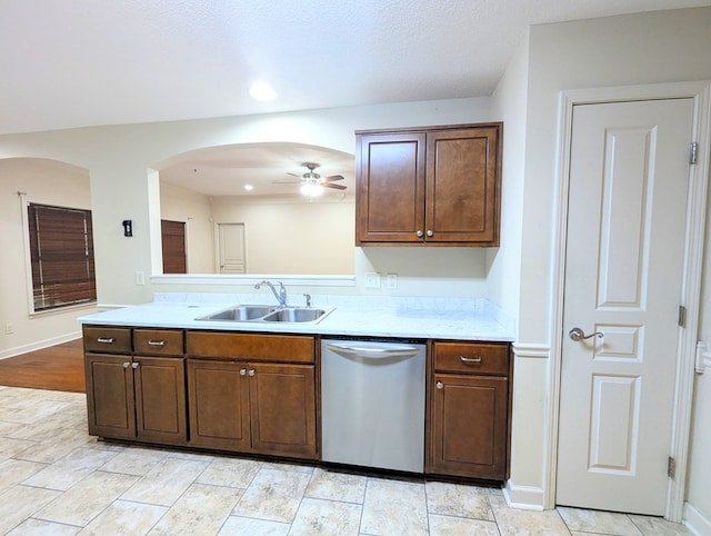 kitchen with arched walkways, a sink, ceiling fan, dishwasher, and baseboards