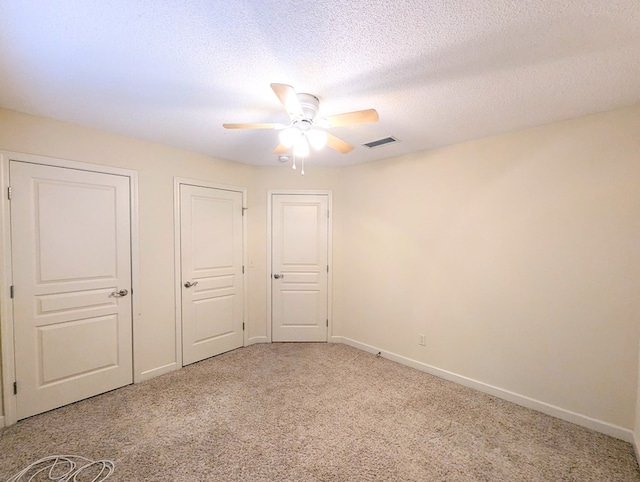 unfurnished bedroom with baseboards, visible vents, light carpet, and a textured ceiling