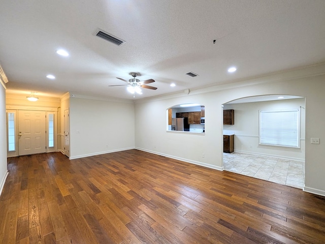 unfurnished living room featuring baseboards, visible vents, crown molding, and hardwood / wood-style floors