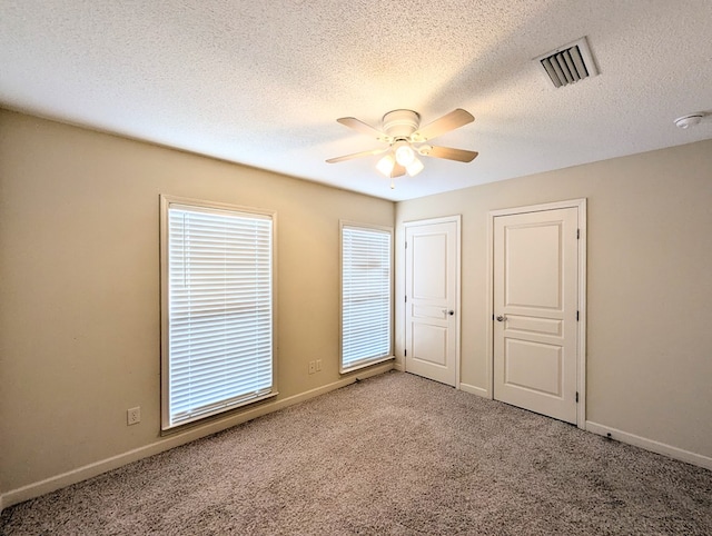 unfurnished bedroom featuring a ceiling fan, baseboards, visible vents, and carpet flooring