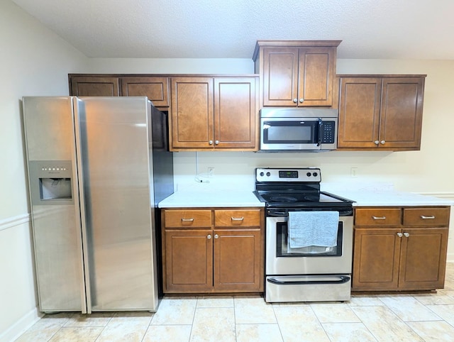 kitchen with light tile patterned floors, stainless steel appliances, a textured ceiling, and light countertops