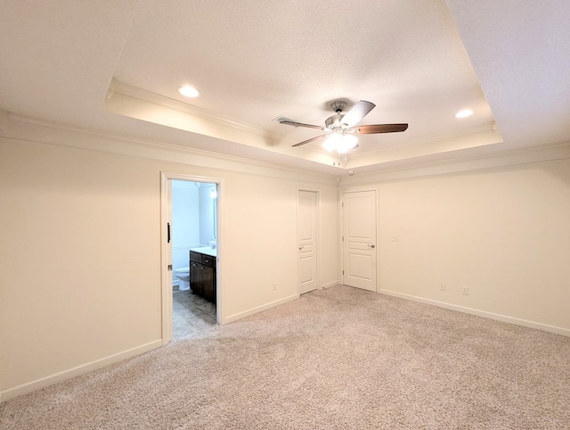 unfurnished room featuring a raised ceiling, ornamental molding, light carpet, a textured ceiling, and baseboards