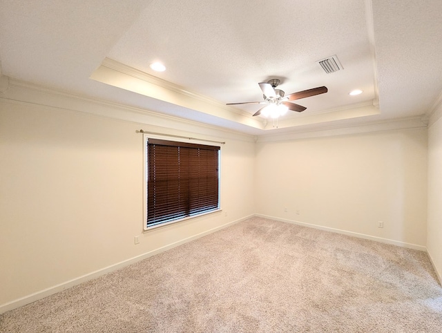 empty room featuring ornamental molding, carpet, a raised ceiling, and visible vents