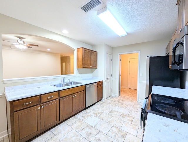 kitchen with arched walkways, visible vents, stainless steel appliances, light countertops, and a sink