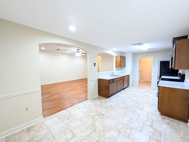 kitchen with stainless steel appliances, arched walkways, light countertops, and ceiling fan