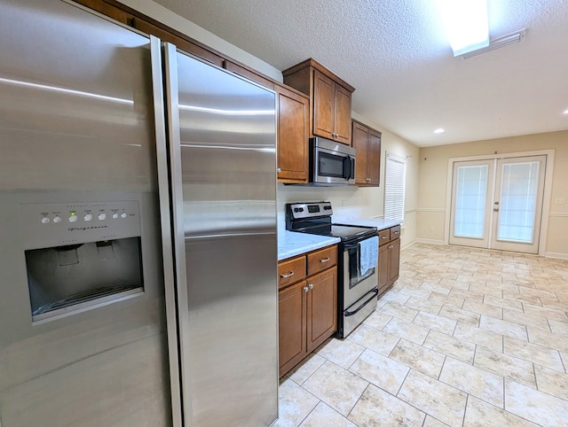 kitchen with french doors, light countertops, appliances with stainless steel finishes, a textured ceiling, and baseboards