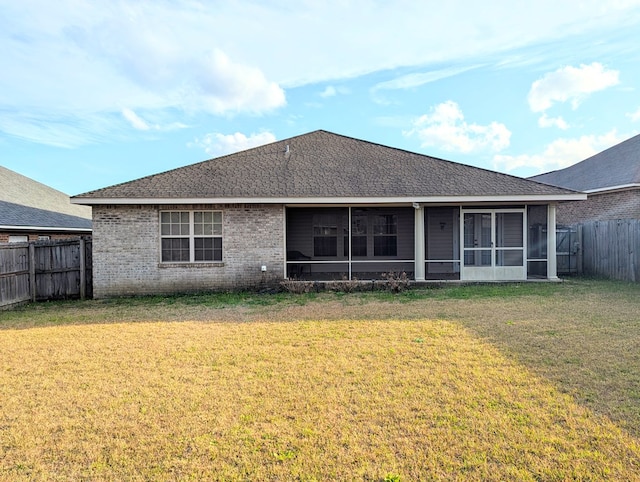 rear view of property with a fenced backyard, brick siding, a sunroom, a yard, and roof with shingles