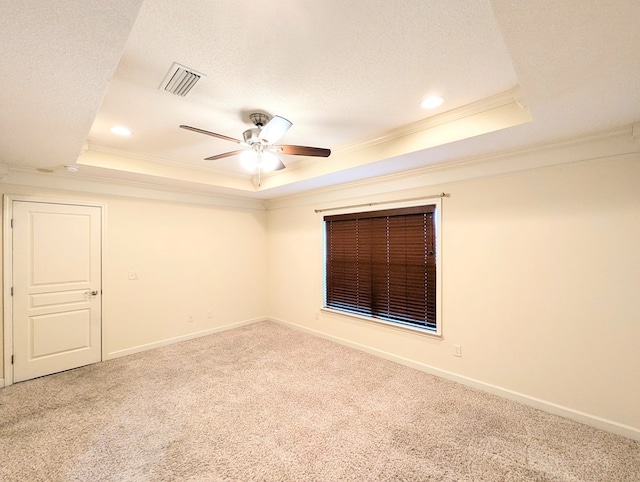 carpeted spare room featuring ornamental molding, a raised ceiling, visible vents, and a textured ceiling