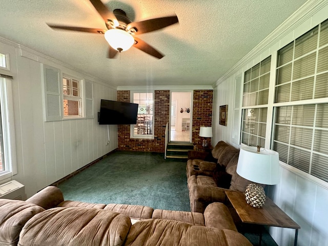 living room with dark carpet, ceiling fan, ornamental molding, a textured ceiling, and a fireplace