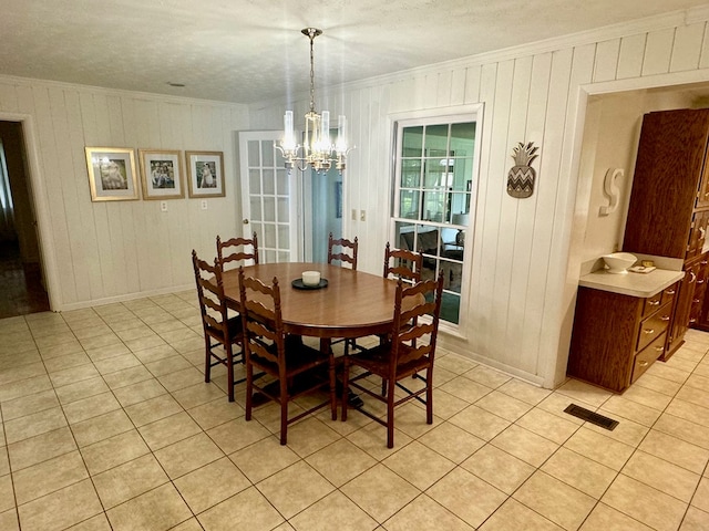 tiled dining space featuring a chandelier and crown molding