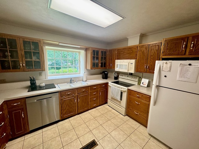 kitchen with light tile patterned flooring, crown molding, white appliances, and sink