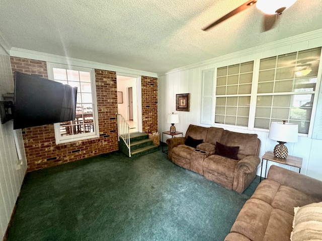 carpeted living room featuring a textured ceiling, ceiling fan, crown molding, and brick wall