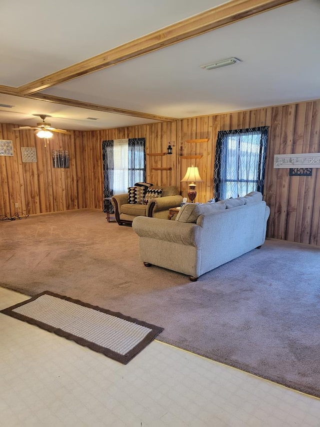 carpeted living room with wooden walls and beam ceiling