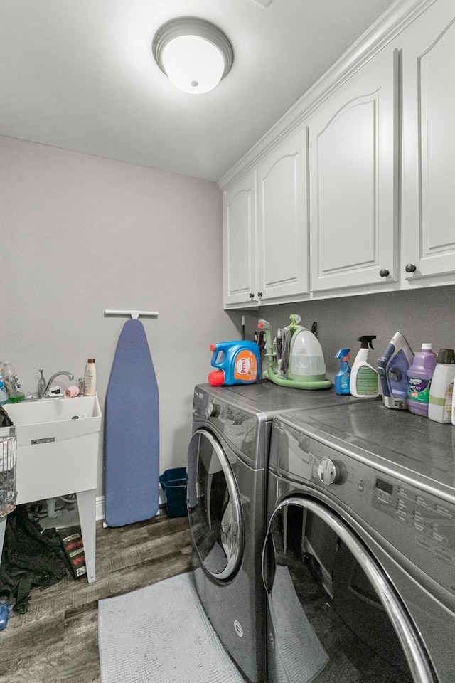laundry room featuring washing machine and clothes dryer, cabinet space, and wood finished floors