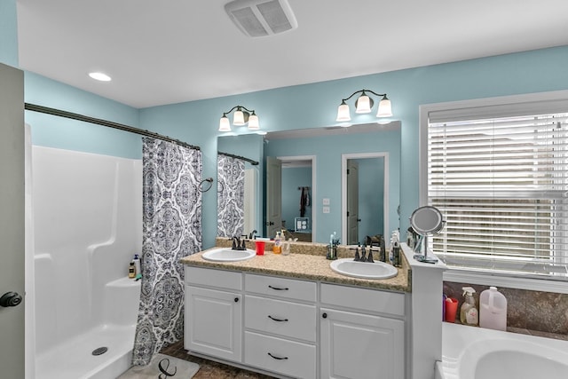 bathroom with visible vents, double vanity, a shower with curtain, a sink, and a healthy amount of sunlight