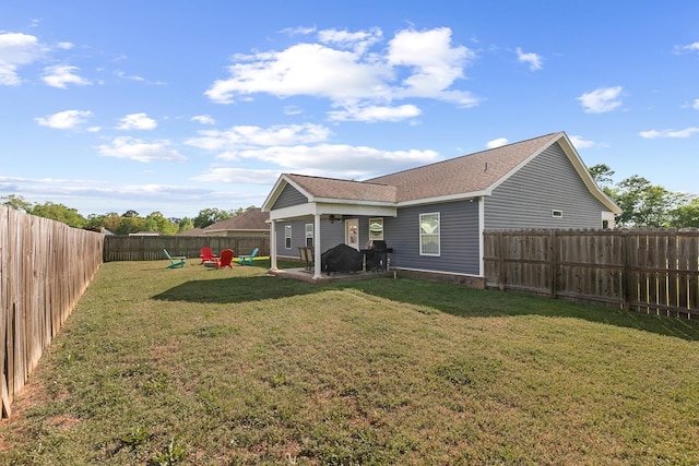 back of house with a fenced backyard, a patio, a shingled roof, and a lawn