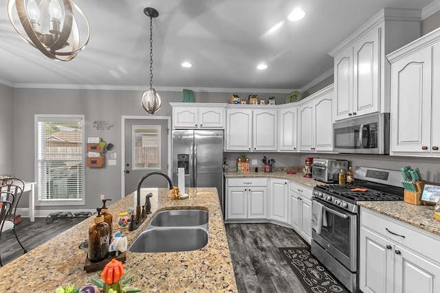 kitchen featuring crown molding, a sink, white cabinets, stainless steel appliances, and decorative light fixtures