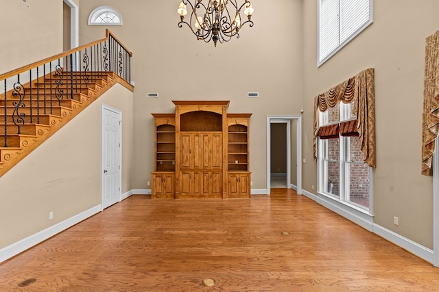601 Edinburgh Way, Dothan, AL 36305 - unfurnished living room with a chandelier, a towering ceiling, plenty of natural light, wood finished floors, and baseboards