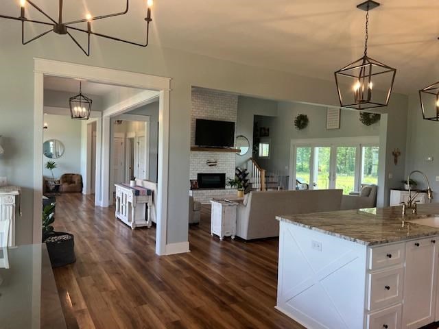 1015 Hardy Rd, Dothan, AL 36301 - kitchen featuring open floor plan, a chandelier, white cabinets, and a brick fireplace