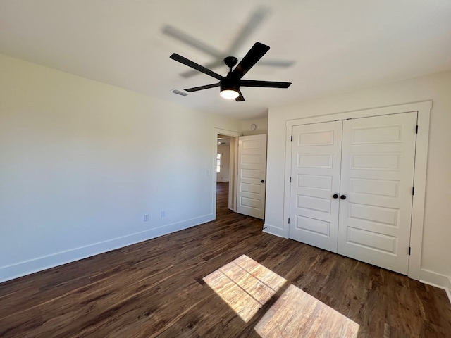 unfurnished bedroom featuring dark wood-type flooring, a closet, and ceiling fan