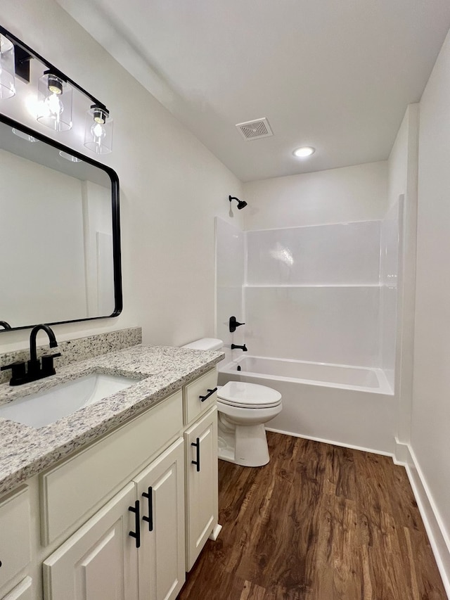 full bathroom with vanity, hardwood / wood-style floors, washtub / shower combination, and toilet