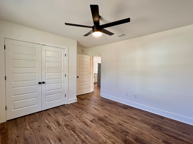 unfurnished bedroom with a closet, dark hardwood / wood-style floors, and ceiling fan