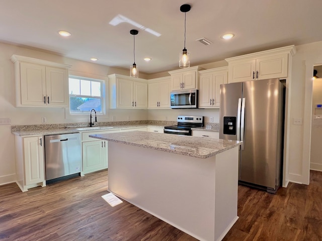 kitchen with appliances with stainless steel finishes, sink, a kitchen island, and white cabinets