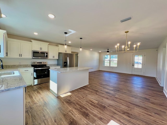 kitchen with appliances with stainless steel finishes, a center island, pendant lighting, and white cabinets