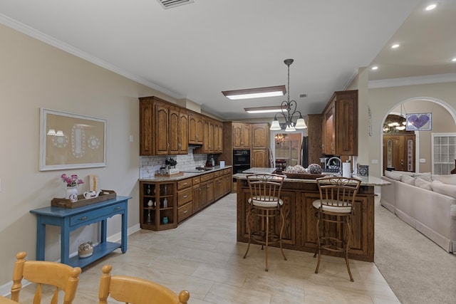 kitchen featuring decorative backsplash, a kitchen breakfast bar, kitchen peninsula, crown molding, and a notable chandelier