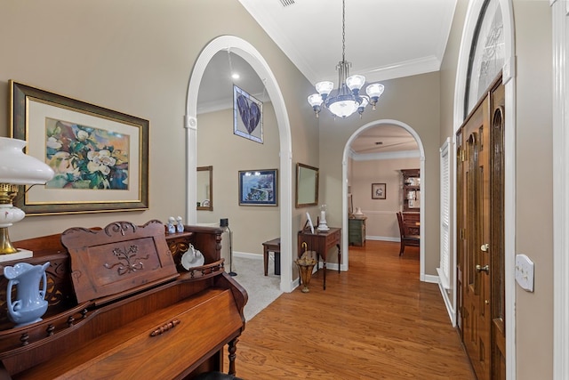 foyer with an inviting chandelier, ornamental molding, and light wood-type flooring