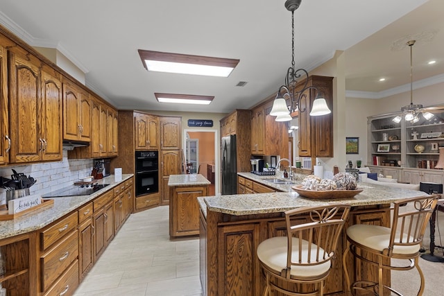 kitchen featuring kitchen peninsula, a kitchen bar, black appliances, decorative light fixtures, and a center island