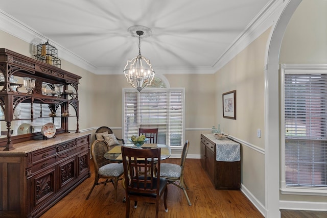 dining area featuring wood-type flooring, an inviting chandelier, and ornamental molding