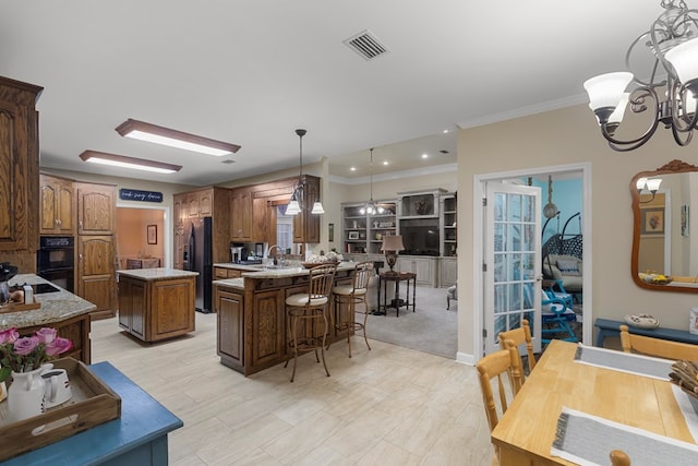 kitchen with a center island, a chandelier, decorative light fixtures, black appliances, and ornamental molding