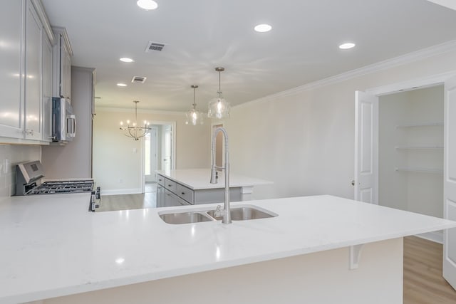kitchen with a sink, stainless steel appliances, gray cabinets, a kitchen breakfast bar, and visible vents