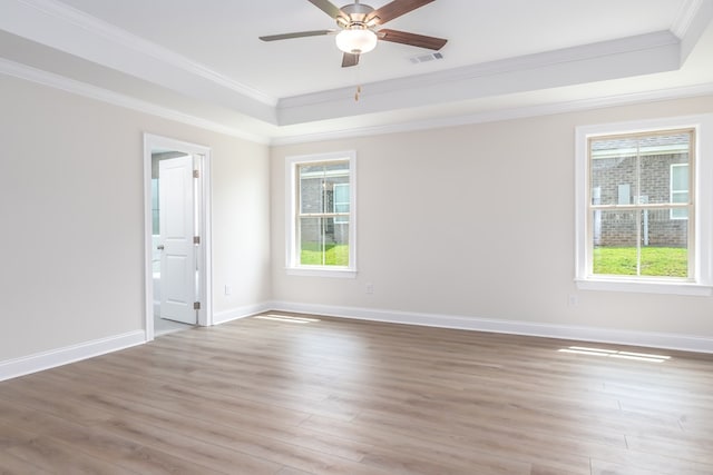 unfurnished room with a tray ceiling, plenty of natural light, visible vents, and light wood-style flooring