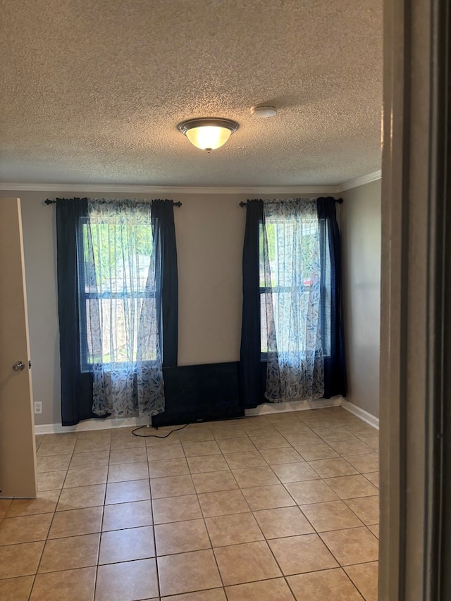 empty room featuring crown molding, a textured ceiling, and light tile patterned floors