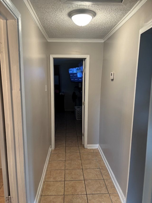 hall featuring ornamental molding, a textured ceiling, baseboards, and light tile patterned floors