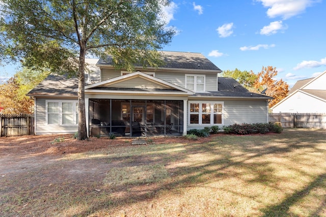 rear view of house featuring a yard and a sunroom