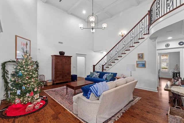 living room featuring beam ceiling, dark wood-type flooring, coffered ceiling, a towering ceiling, and a chandelier