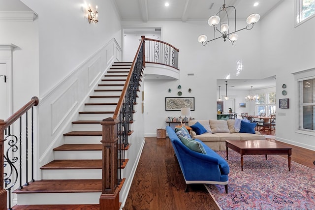 living room featuring crown molding, a towering ceiling, dark wood-type flooring, and a notable chandelier