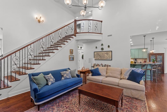 living room featuring a high ceiling, dark wood-type flooring, and a notable chandelier