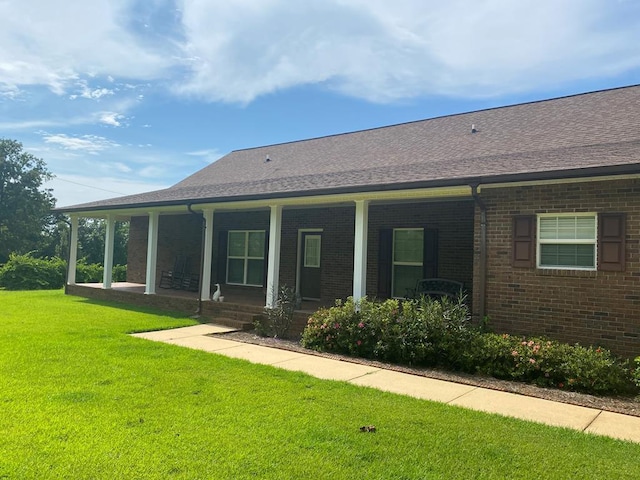 rear view of property featuring a porch and a lawn