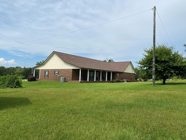 rear view of property featuring a yard and central air condition unit