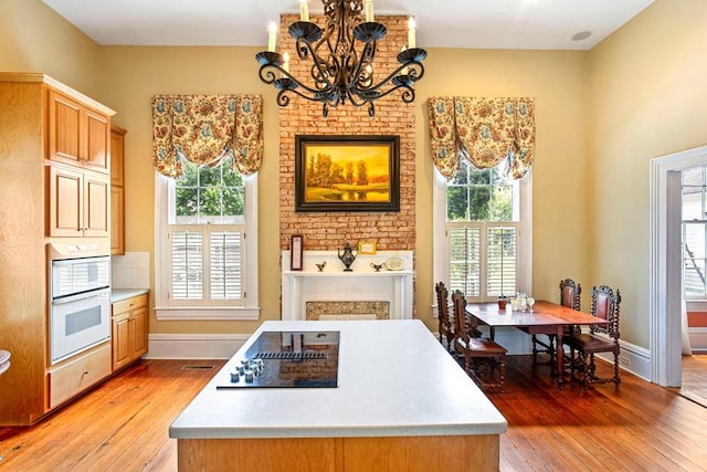 kitchen featuring double oven, decorative light fixtures, a notable chandelier, and light wood-type flooring