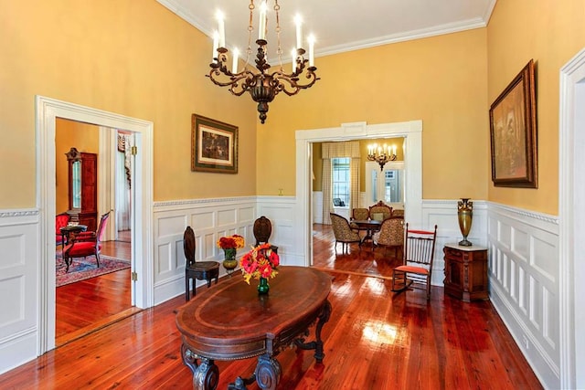 dining area featuring hardwood / wood-style floors, a towering ceiling, a chandelier, and ornamental molding