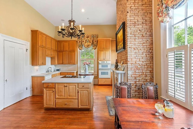 kitchen with double oven, dark hardwood / wood-style floors, a kitchen island, and hanging light fixtures