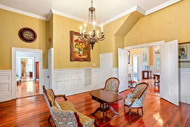 living area featuring a high ceiling, hardwood / wood-style flooring, crown molding, and a notable chandelier