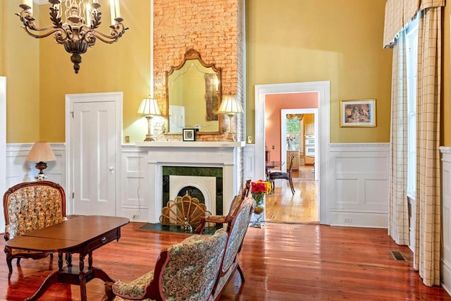 sitting room featuring a chandelier, a towering ceiling, and hardwood / wood-style flooring