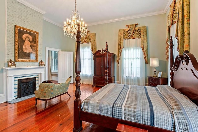 bedroom with a notable chandelier, a large fireplace, wood-type flooring, and ornamental molding