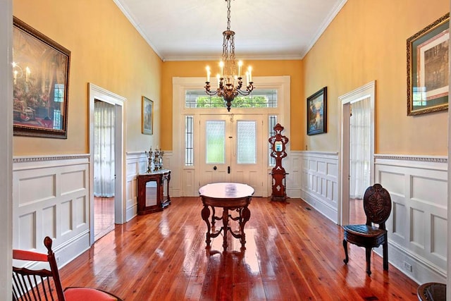 dining room with crown molding, hardwood / wood-style floors, french doors, and an inviting chandelier